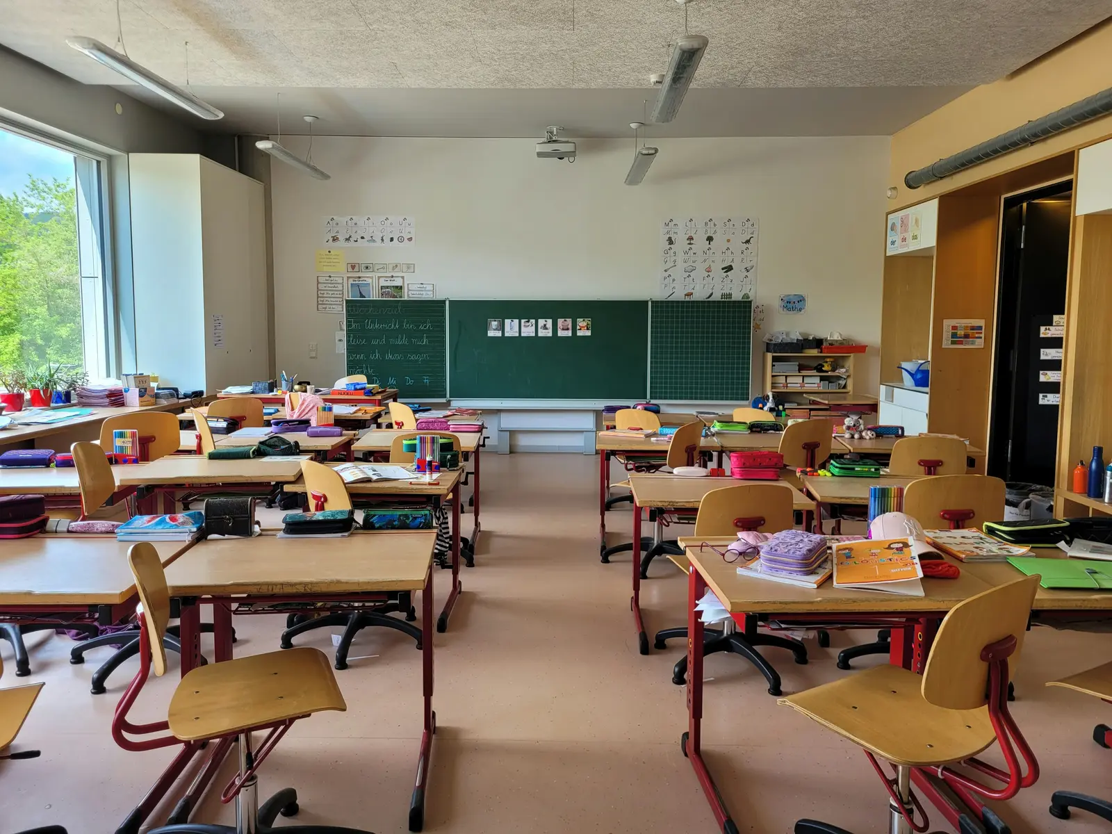 An empty classroom with desks, chairs and books laid out